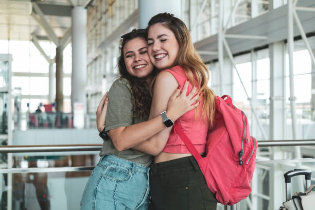 Two friends in the airport. Photo of two friends in an airport. Young women. airport hug stock pictures, royalty-free photos & images