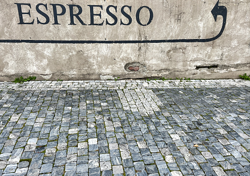 espresso, espresso sign with a black arrow on wall at street with Cobblestoned pavement. background for cafe or coffee. entrance of a cafe on wall
