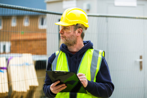 Construction worker examining documents on clipboard stock photo