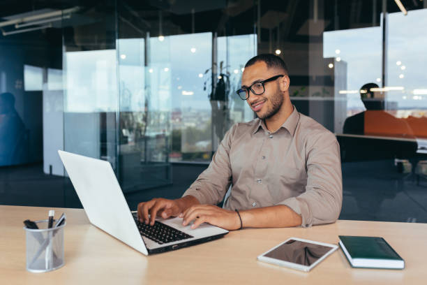 istock African american programmer at work with laptop inside office, man in glasses and casual writing code for programs 1460835060