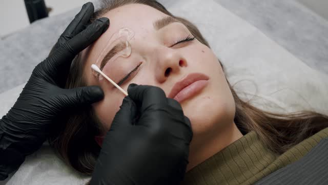 Dark pigment is injected under skin. Eyebrow tattoo in beauty salon.