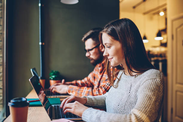 istock Glad female freelancer using laptop near coworker 1460838848