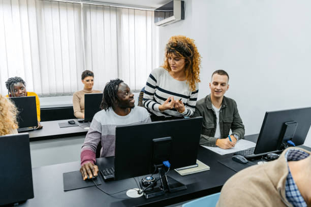 istock Mid Adult Female Teacher Helping Students In A Programing Class 1460841387