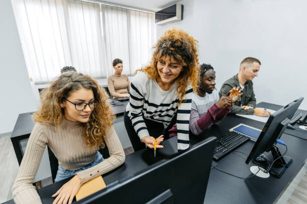 istock Mid Adult Female Teacher Helping Students In A Programing Class 1460841503
