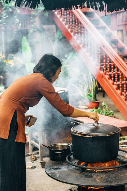 young vietnamese woman is cooking on open fire in restaurant in north vietnam