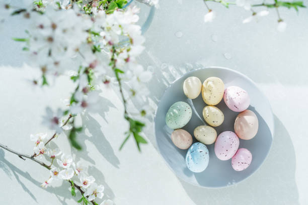 istock Top view colored easter eggs on the gray plate, blooming tree branch in vase and flower petals on the white table. Happy Easter and springtime card. Minimalism and simplicity. Selective focus. 1460847064
