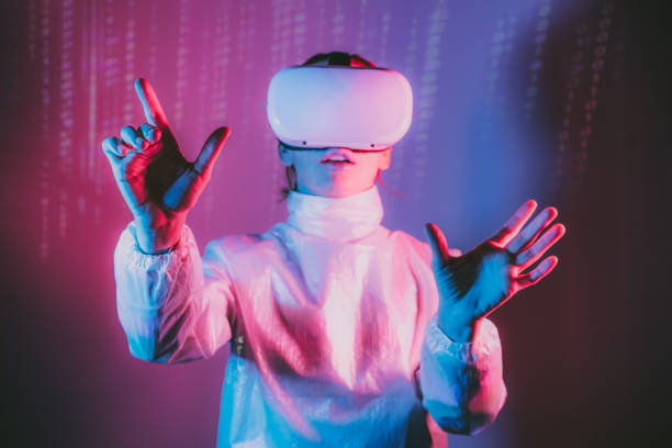 istock Metaverse concept. Selective Focus on Woman's hands in holographic clothes and vr glasses on matrix code background. Virtual reality headset, trying to touch something with hand in pink blue colors 1460847703