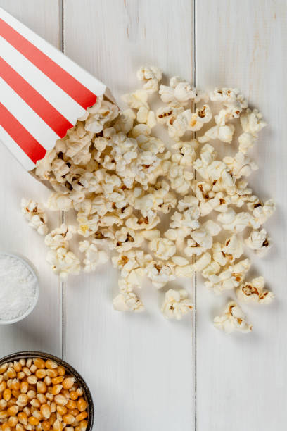 istock popcorn bag, popcorn kernels and salt on a white wooden table, top view 1460847833