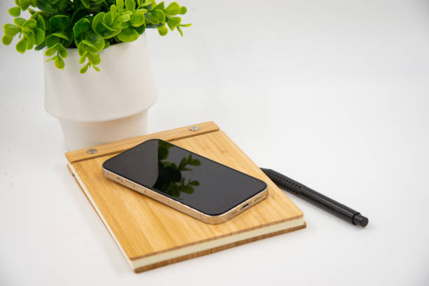 istock Mobile smart phone with blank screen of gadget on notebook. Digital cell phone with copy space area on white background with pencil and leaf 1460850332