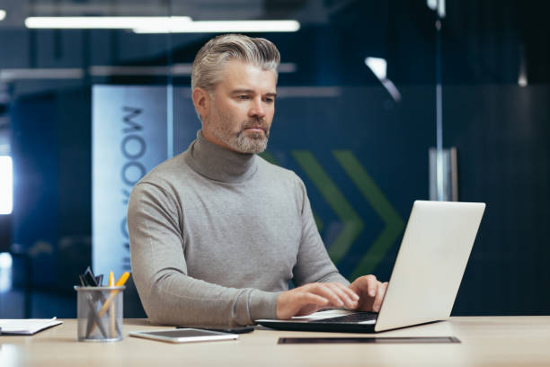 istock Serious and pensive mature investor working inside modern office, senior gray-haired businessman using laptop at work, male boss at work sitting at desk 1460851661