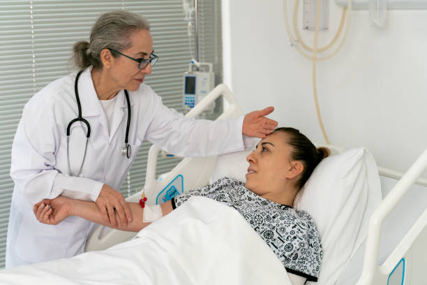 istock Female senior doctor checking on a hospitalized young patient lying down on bed 1460852641