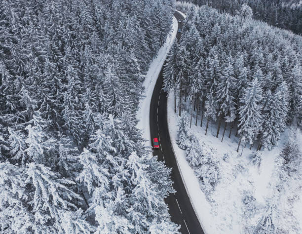 istock Snow-covered trees in the forest and red car on the road line in the mountains. Winter landscape in the mountains. Aerial drone panoramic photo. 1460856499