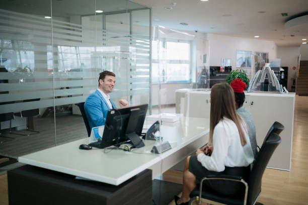 Car dealer with customers at desk in showroom stock photo