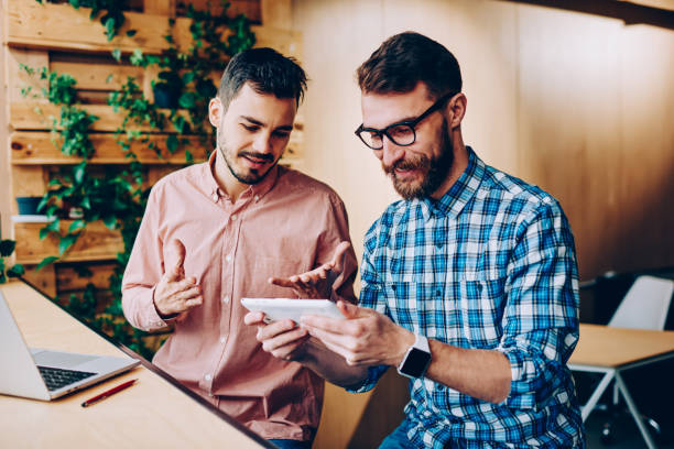 istock Content remote worker showing phone to partner in cafe 1460859749