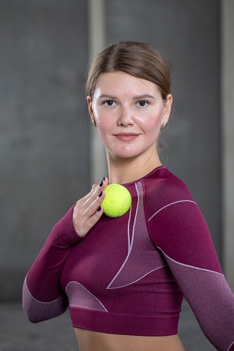 A young woman in sportswear does self-massage and presses on trigger points with a ball after training to restore and relax muscles. MFR, Pilates, rehabilitation gymnastics.