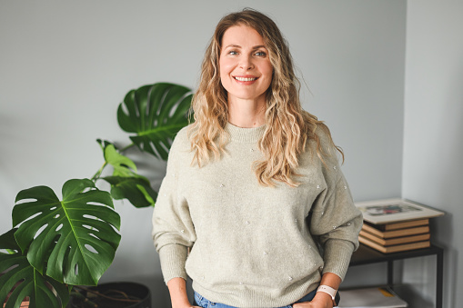 Happy young businesswoman in white shirt pointing aside while standing in front of camera in isolation