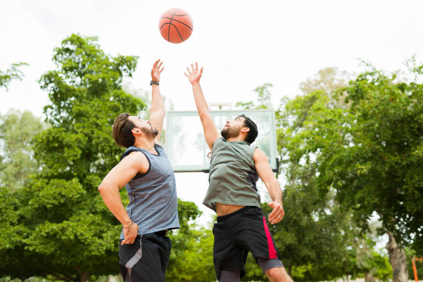 Fitness young men jumping to catch the ball while playing a one on one basketball game