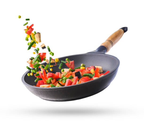 istock Fresh chopped vegetables mix flying in a pan, isolated on white background 1460866538