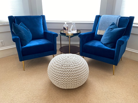 Blue velvet chairs waiting to be sat in with bourbon and white pouf