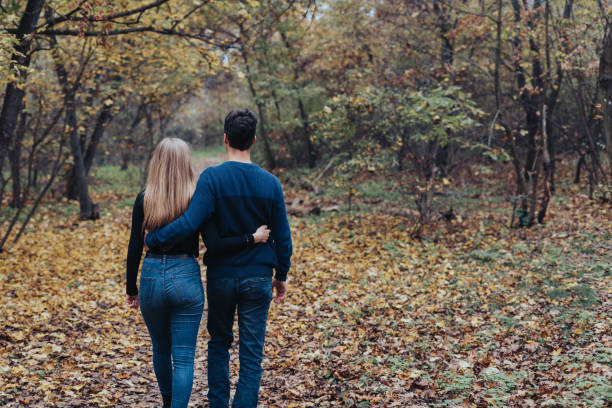 istock Young couple walking in a forest holding each other 1460868103