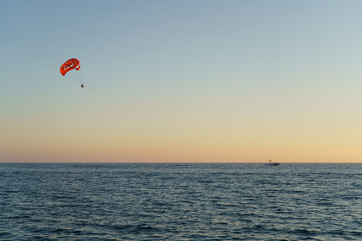 People Parasailing Over Sea Against Sky During Sunset
