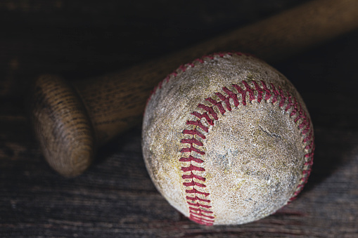 An old baseball with a wood baseball bat.