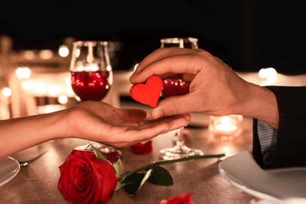 Man giving woman a heart at a romantic dinner setting stock photo