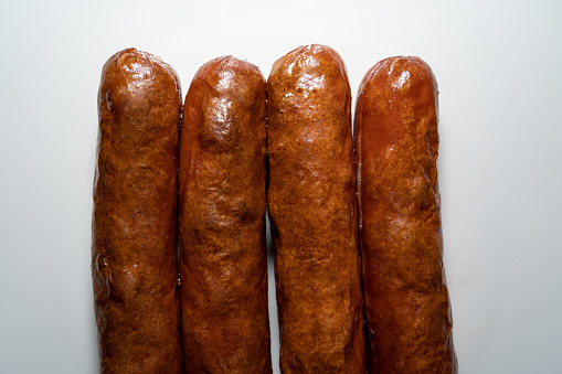 Four brown fried sausages with a white background