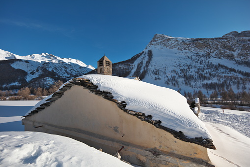 Maljasset, a hamlet in the Vallon de Maurin well known to hikers, is located in the Alpes de Haute Provence in upper Ubaye.\n\n  In the foreground the gable wall and the snow-covered slates of the roof of the chapel of the penitents with behind the bell tower of the church of Saint-Antoine du désert rebuilt in the 16th century on foundations from the 12th.\nThe summit on the right is the head of Miéjour 2689m