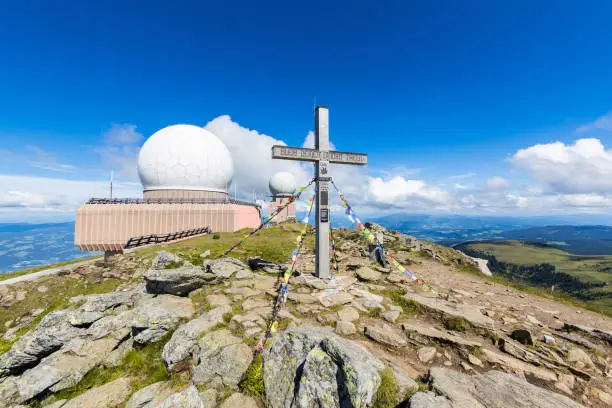 The mountain cross of the Großer Speikkogel with the Goldhaube radar station buildings in the background