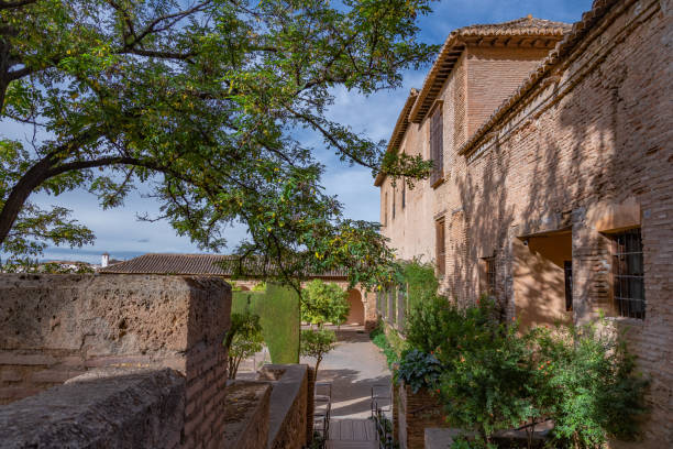 View of the Moorish Alhambra de Granada complex in Granada from the inside. Sabika Hills. View of the courtyards of the complex, fortified bricks walls, narrow passages and nooks and usual places of rest, Granada, Andalusia, Spain