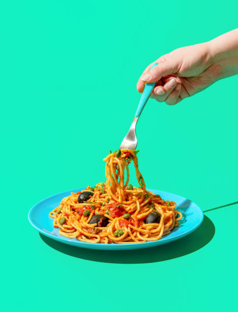 istock Eating spaghetti puttanesca, a vegan pasta dish, minimalist on a green background 1460878508