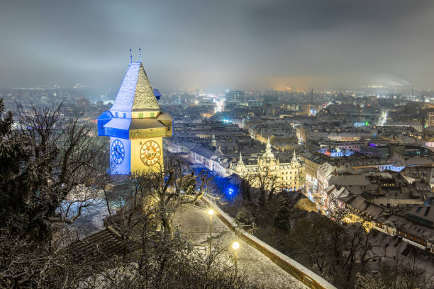 le célèbre monument de graz en autriche, la tour de l’horloge du schloßberg en hiver illuminée aux couleurs de l’ukraine - graz clock tower clock austria photos et images de collection