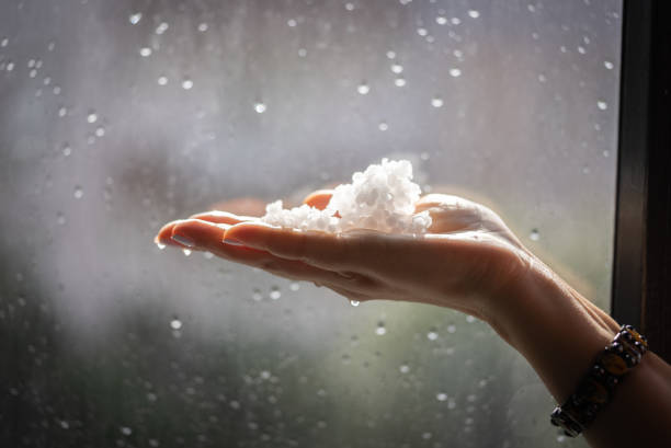 Woman's hands holding hail snow front of window