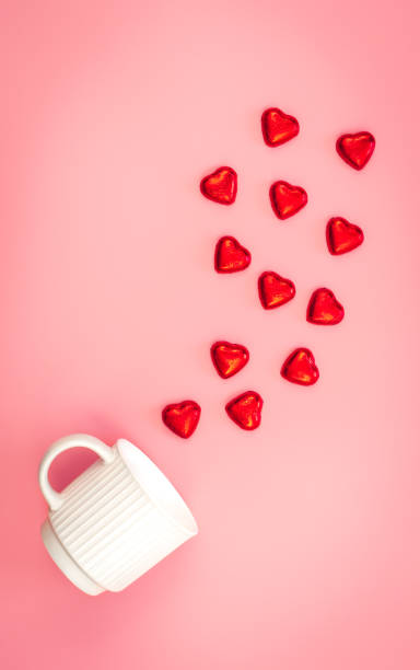 istock A cup and scattered heart-shaped sweets on a pink background, flat lay. 1460881636