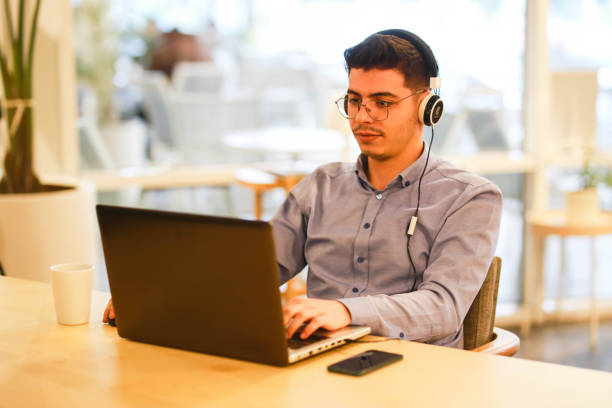 istock young man working remotely hybrid with laptop in cafe 1460884948