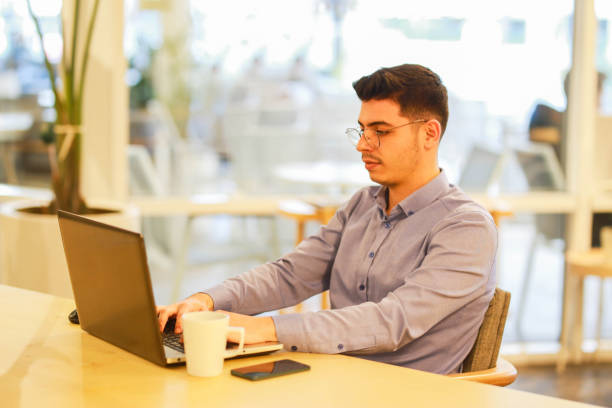 istock young man working remotely hybrid with laptop in cafe 1460885753