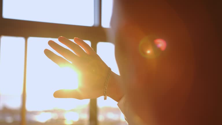 Male hand playing with sunlight glare coming through window. Close up