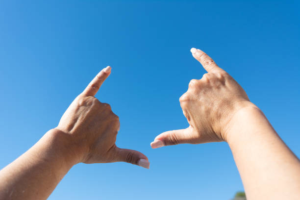 istock woman's hands showing surfer sign against blue sky background 1460889992
