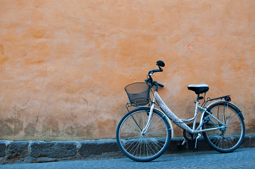 Bicycle with basket leaning against an orange wall. Orvieto, Italy