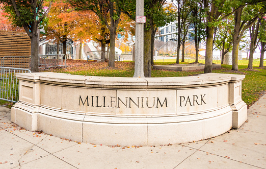 Entrance to Millennium Park, Chicago, on a colorful, late fall day. Showing Millennium Park etched in stone, trees in background.