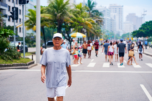senior adult man doing walk exercise on the beach avenue in Ipanema