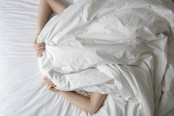 istock Girl lying in bed covering her face with blanket 1460901768