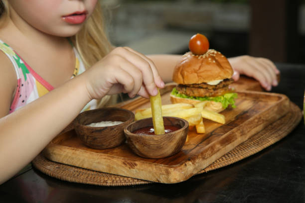Little girl eating french fries with tomato sauce at the restaurant stock photo