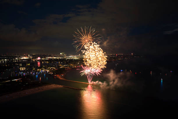 vista aérea de fogos de artifício brilhantes explodindo com luzes coloridas sobre a costa do mar no feriado do dia da independência dos eua - exploding celebration multi colored colors - fotografias e filmes do acervo