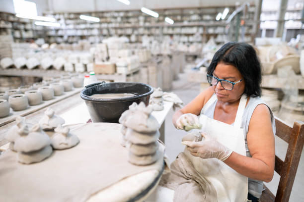 istock Worker using a sponge to clean clay lids in a ceramics factory 1460906332