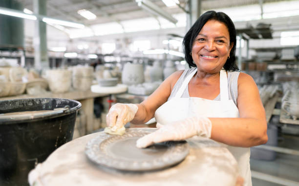 istock Smiling worker cleaning a clay plate in a ceramics factory 1460906364