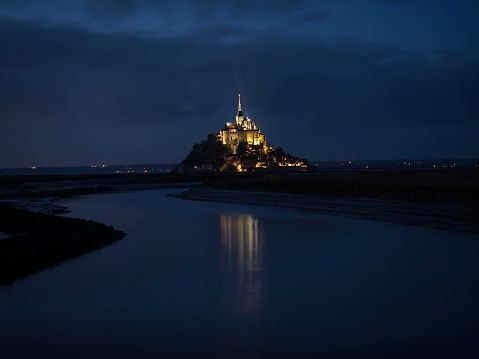 Panorama landscape night view of Mont Saint Michel famous remote isolated island rock castle town in Normandy France Europe