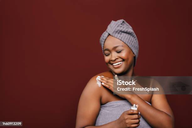 A Happy Beautiful Woman Wrapped In A Towel Taking Care Of Her Skin With Her Eyes Closed Stock Photo - Download Image Now