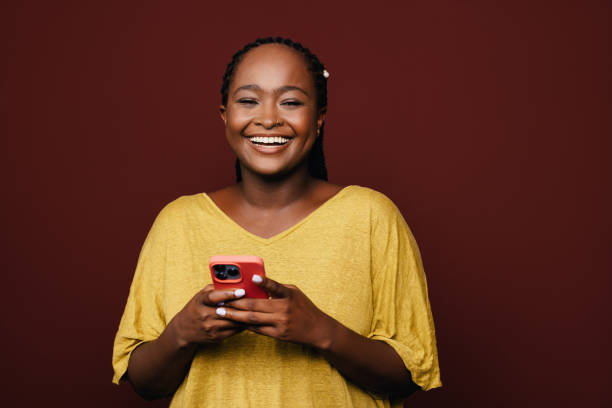 istock A Beautiful Businesswoman With Braids Looking At Camera While Using Her Mobile Phone 1460913280